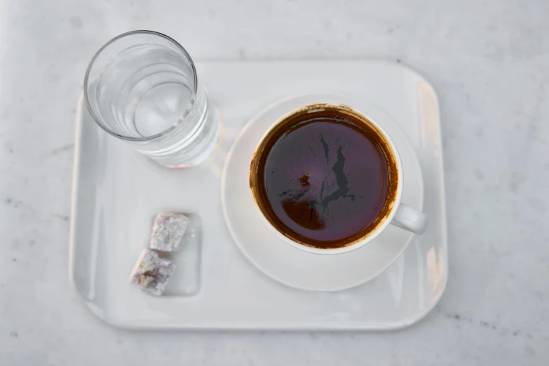 a cup of coffee sitting on top of a white tray, inspired by Constantine Andreou, hurufiyya, ice coffee, square, traditional medium, thumbnail