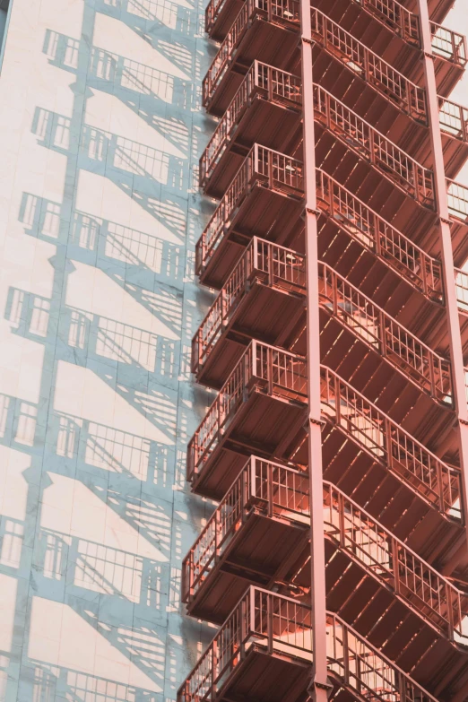 a tall red fire escape staircase next to a tall building, inspired by Elsa Bleda, pexels contest winner, sunfaded, copper, half image, under construction