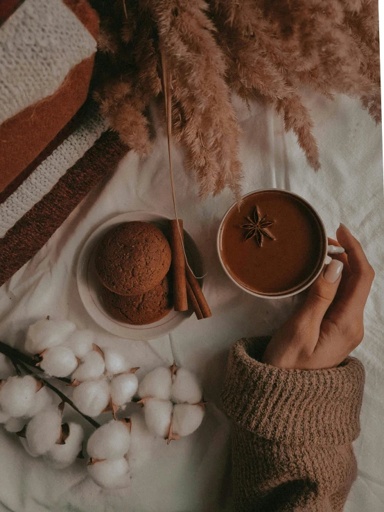 a person holding a cup of coffee on a bed, by Lucia Peka, aestheticism, cinnamon, avatar image