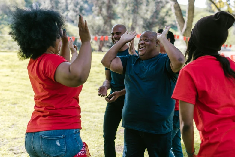 a group of people standing on top of a lush green field, dancing a jig, community celebration, brown skin man with a giant grin, sydney park