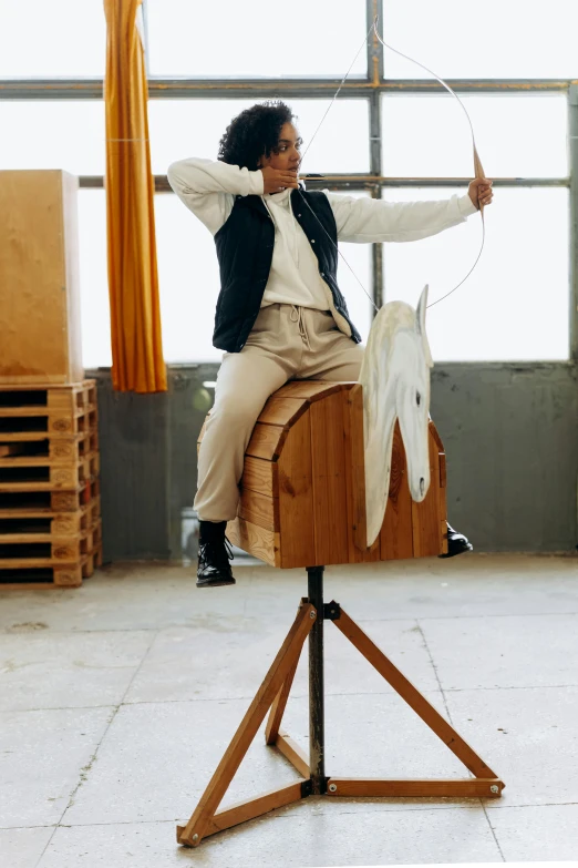 a man riding on the back of a wooden horse, by Marina Abramović, unsplash, in a workshop, portrait of willow smith, rocking out, promo image