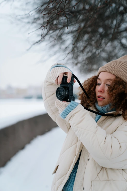 a woman taking a picture with a camera in the snow, pexels contest winner, wearing a turtleneck and jacket, film color photography, gif, college