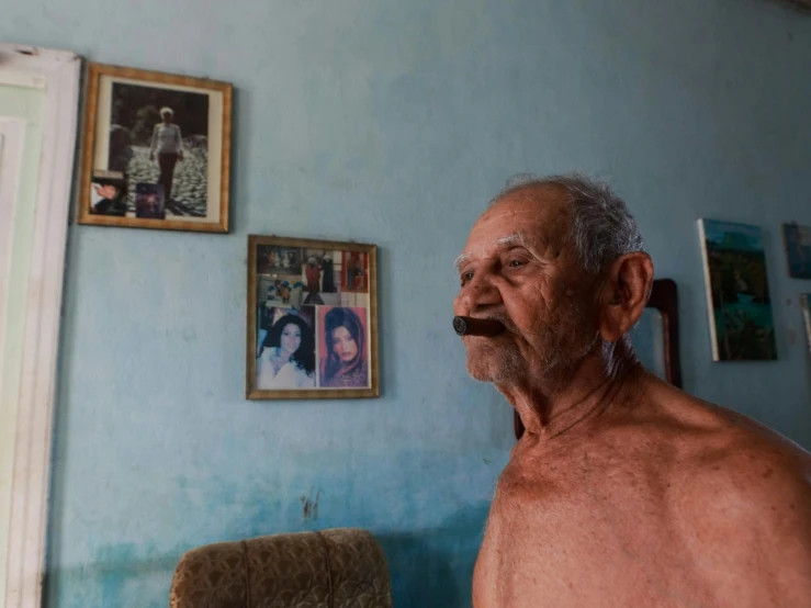 a man standing in a room with pictures on the wall, a portrait, pexels contest winner, photorealism, cuban setting, oldman with mustach, pixelated, multiple stories