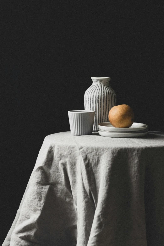 a white plate sitting on top of a table next to a vase, a still life, trending on unsplash, hyperrealism, linen canvas, dark grey and orange colours, cups and balls, medium format