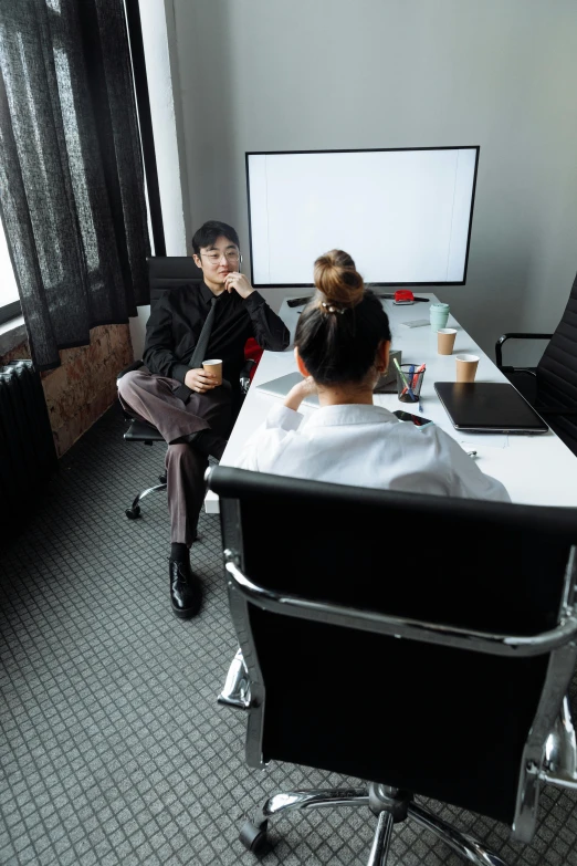 a group of people sitting around a table in a room, on a desk