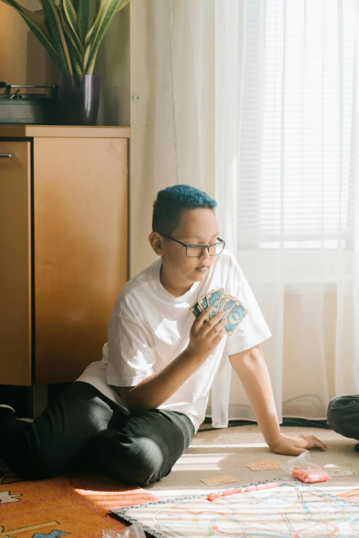 a man sitting on the floor playing a game, inspired by Nan Goldin, pexels contest winner, visual art, blue mohawk, asian female, with glasses, standing in corner of room