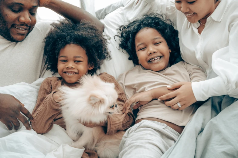 a family laying in bed with a cat, pexels contest winner, two girls, varying ethnicities, ragdoll cat, avatar image