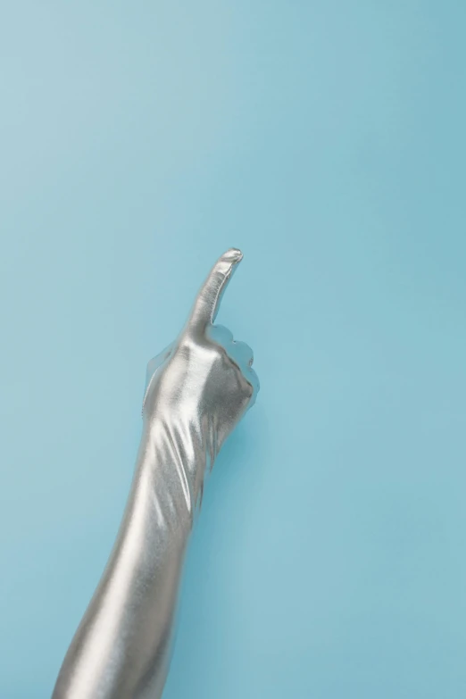 a close up of a person's hand on a blue background, an album cover, inspired by Robert Mapplethorpe, trending on pexels, magic realism, made out of shiny silver, middle finger, metallic neoprene woman, transparent body