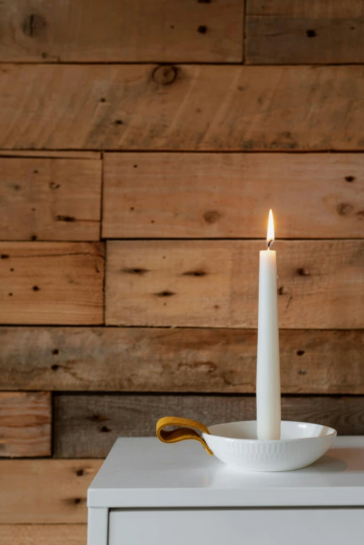 a white candle sitting on top of a white table, by Jessie Algie, white plank siding, holding a candle holder, dimly lit, glazed