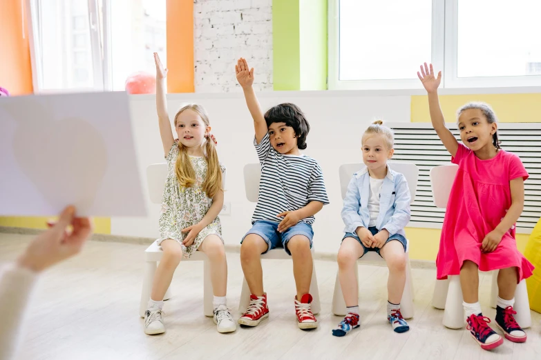 a group of children sitting on a bench with their hands in the air, sitting in a waiting room, school curriculum expert, cutest, playrix