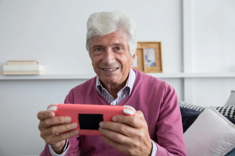 a man sitting on a couch holding a cell phone, a photo, inspired by senior environment artist, pexels contest winner, pixel art, holding a nintendo switch, pleasant face, alex trebek, nursing home