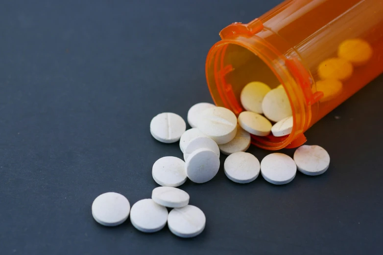 pills spilling out of an open prescription bottle, by Matt Cavotta, pexels, antipodeans, orange and white, round, on a gray background, on a wooden tray