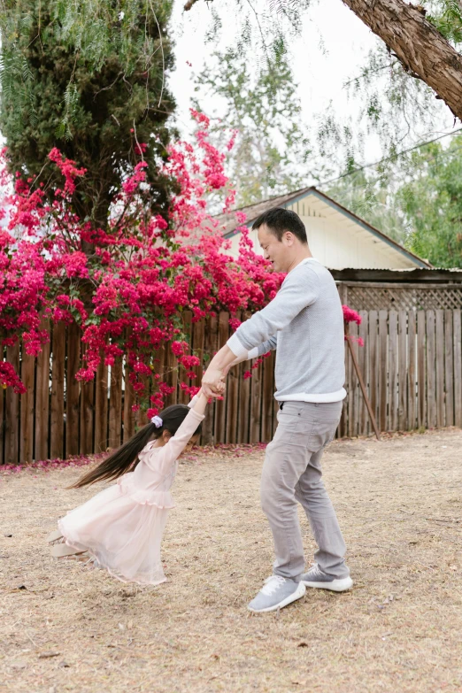 a man and a little girl playing with a kite, inspired by Cui Bai, pexels contest winner, prima ballerina in rose garden, white picket fence, john cho, bougainvillea