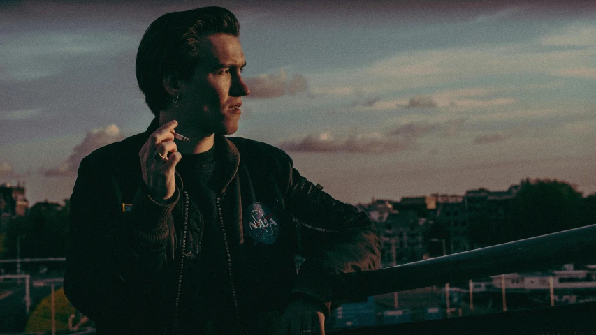 a man standing on a balcony talking on a cell phone, an album cover, by Emma Andijewska, unsplash, wearing a leather flight jacket, pewdiepie, smoking a joint, profile image