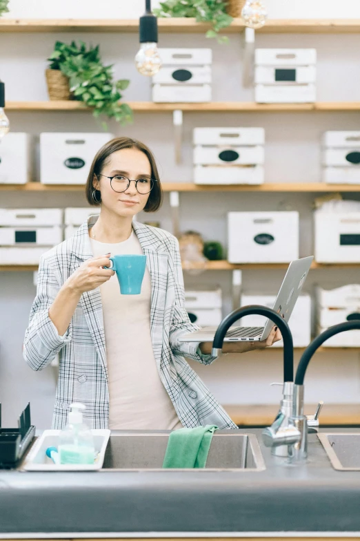 a woman standing in a kitchen holding a cup, pexels contest winner, nerdy appearance, inspect in inventory image, standing next to water, at checkout