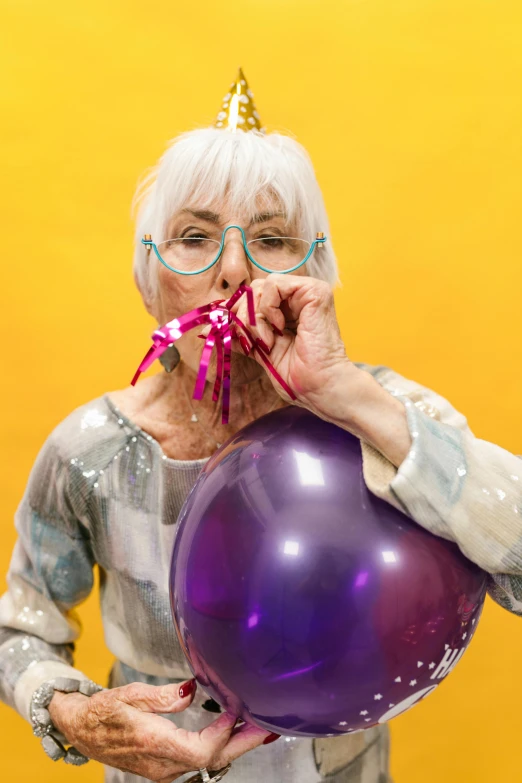 a woman holding a purple balloon in front of her face, by Ellen Gallagher, trending on pexels, hyperrealism, a silver haired mad, holding a yellow toothbrush, at a birthday party, wrinkly