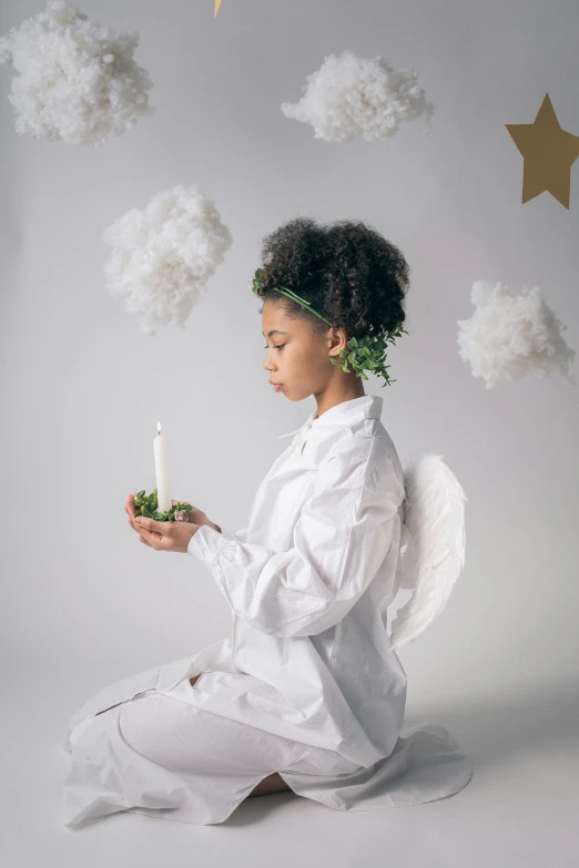 a little girl dressed as an angel holding a candle, inspired by Marie Angel, pexels contest winner, with afro, teen elf, white backdrop, peaceful cloud