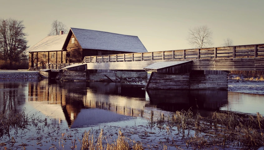 a wooden bridge over a body of water, a picture, by Jesper Myrfors, unsplash, romanticism, barn, outside winter landscape, brown, historical photo