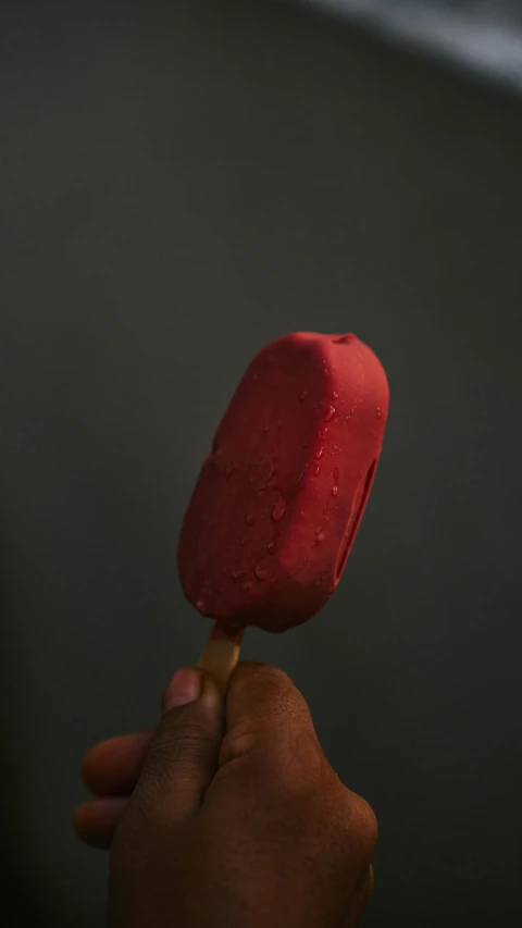 a close up of a person holding a popsicle, by Doug Ohlson, dark red color, dark-skinned, high quality photo, potato