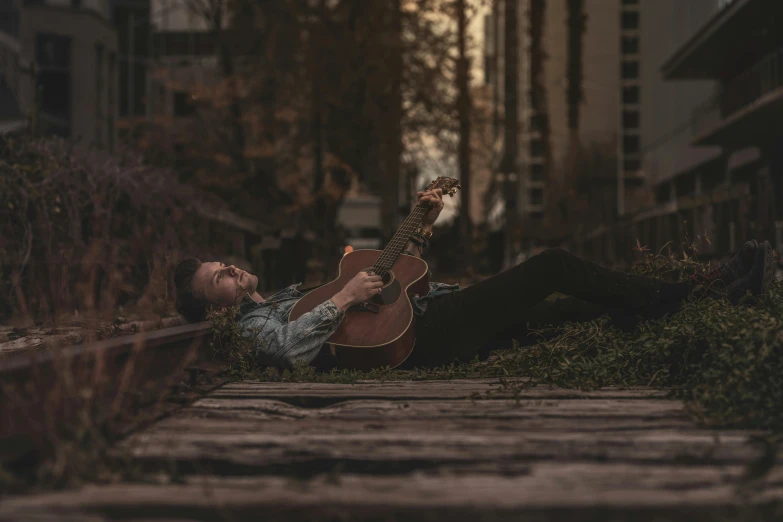 a man laying on the ground with a guitar, inspired by Maxwell Gordon Lightfoot, pexels contest winner, early evening, lachlan bailey, corinne day, full body pose