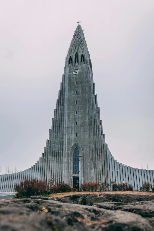 a very tall building with a clock on top of it, inspired by Þórarinn B. Þorláksson, unsplash, futuristic church, 3/4 front view, 2045, concrete building