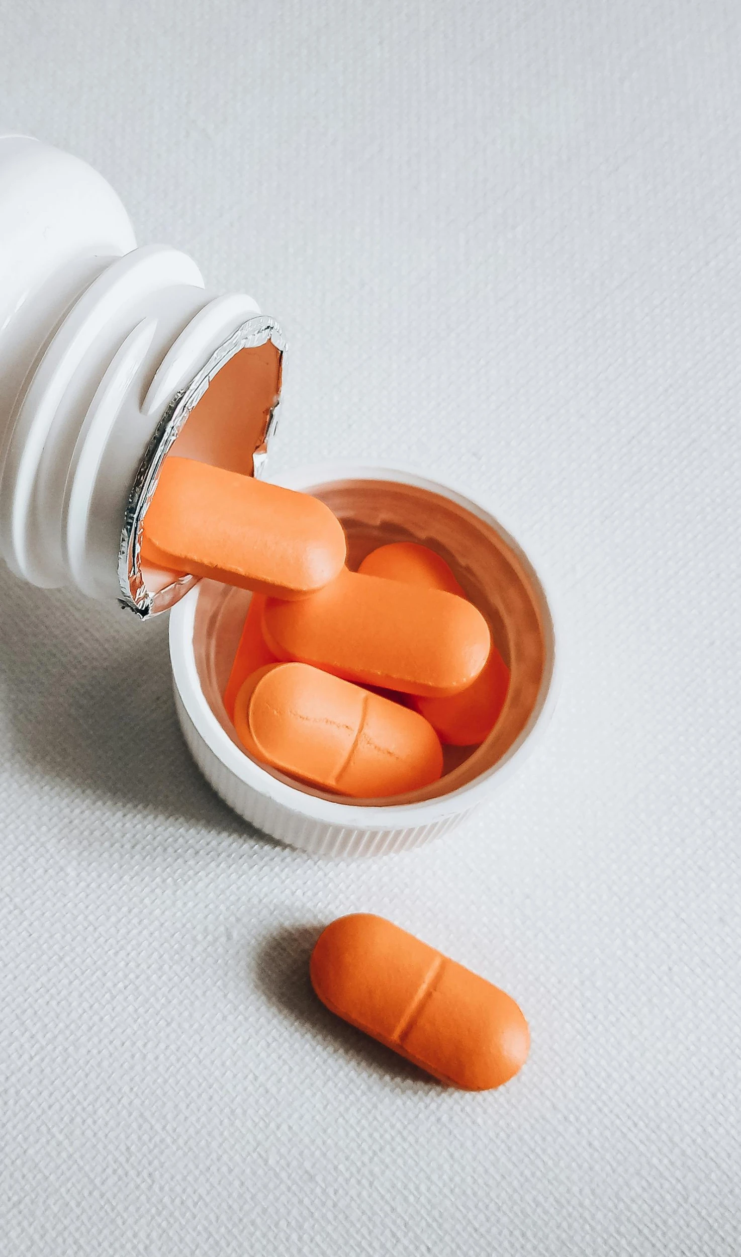 an open pill bottle with orange pills spilling out of it, by Nicolette Macnamara, pexels, antipodeans, instagram post, grey orange, made of plastic, teaser