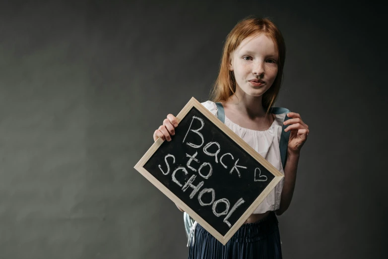 a little girl holding a chalk board that says back to school, pixabay, portrait of a red haired girl, 1 6 years old, thumbnail, 1 5 6 6