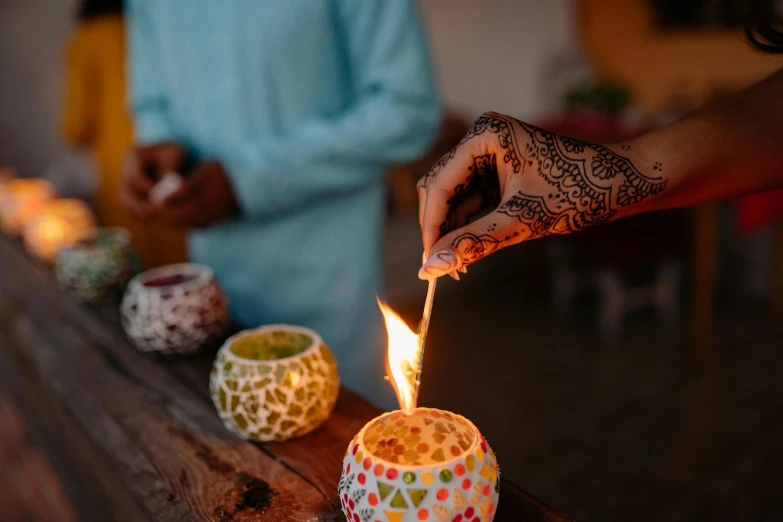 a close up of a person lighting a candle, trending on pexels, hindu ornaments, flares, small fire, mixed art