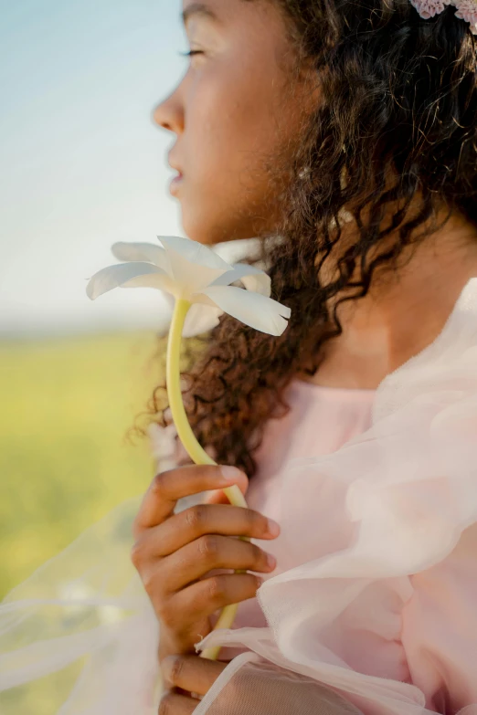 a little girl in a pink dress holding a flower, inspired by Marie Laurencin, unsplash, african american young woman, spring light, curls, detail shot