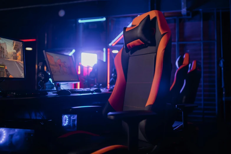 a gaming chair sitting in front of a computer monitor, a portrait, dark blue + dark orange, backroom background, orange and black, glowing red