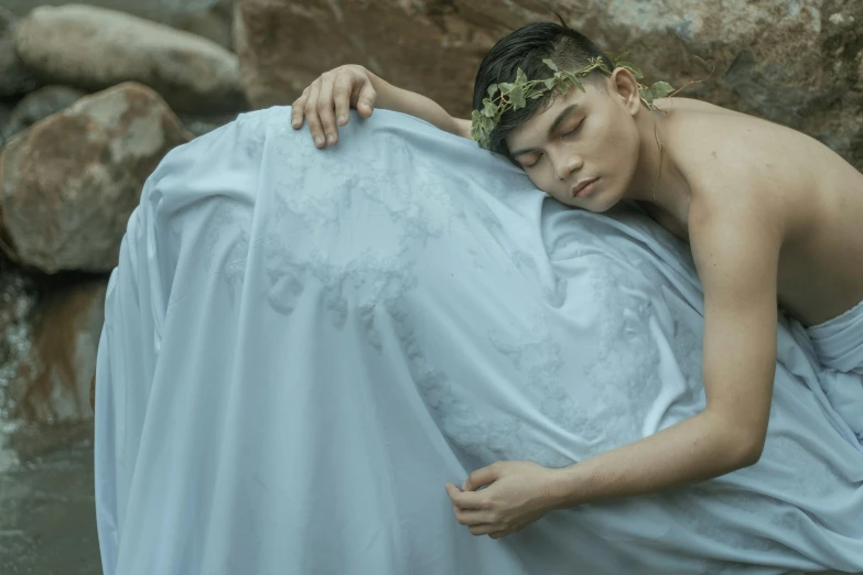 a man that is laying down in some water, an album cover, inspired by Ren Hang, pexels contest winner, art photography, wearing a luxurious silk cloak, wearing a light grey crown, non binary model, javanese mythology