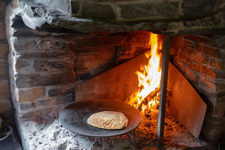 a pizza sitting on top of a pan in front of a fire, private press, shepherd's crook, loaves, thumbnail, exterior shot