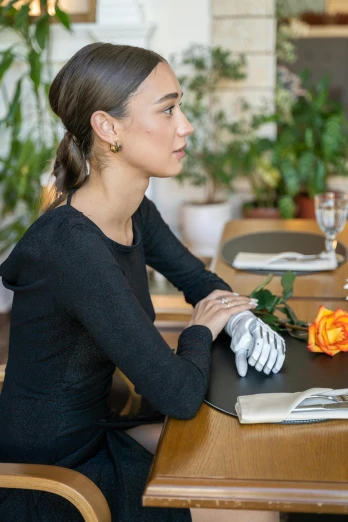 a woman sitting at a table in a restaurant, inspired by Wilhelm Hammershøi, romanticism, wearing gloves, curated collections, black, flowers