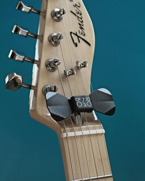 a close up of a guitar neck on a blue background, by Glennray Tutor, bauhaus, slate, mini model, black bowtie, 3d printed