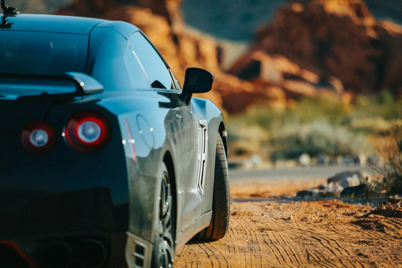 a black sports car driving down a dirt road, a photo, unsplash, high-body detail, gtr xu1, moab, view from the side”