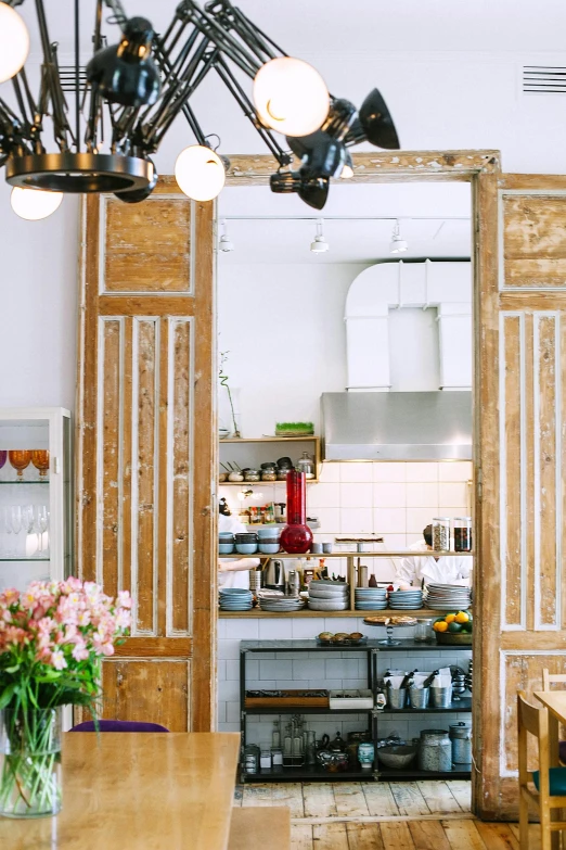 a dining room table with a vase of flowers on it, inspired by Barthélemy Menn, unsplash, wood door, chefs table, inside a cluttered kitchen, storefront