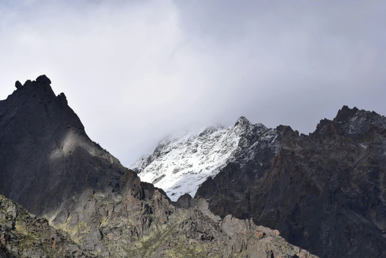 a group of people standing on top of a mountain, by Muggur, pexels contest winner, hurufiyya, with snow on its peak, grey, in between a gorge, andes