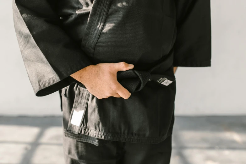 a close up of a person wearing a black jacket, inspired by Kanō Hōgai, unsplash, shin hanga, karate outfit, holster, bottom body close up, detailed product image