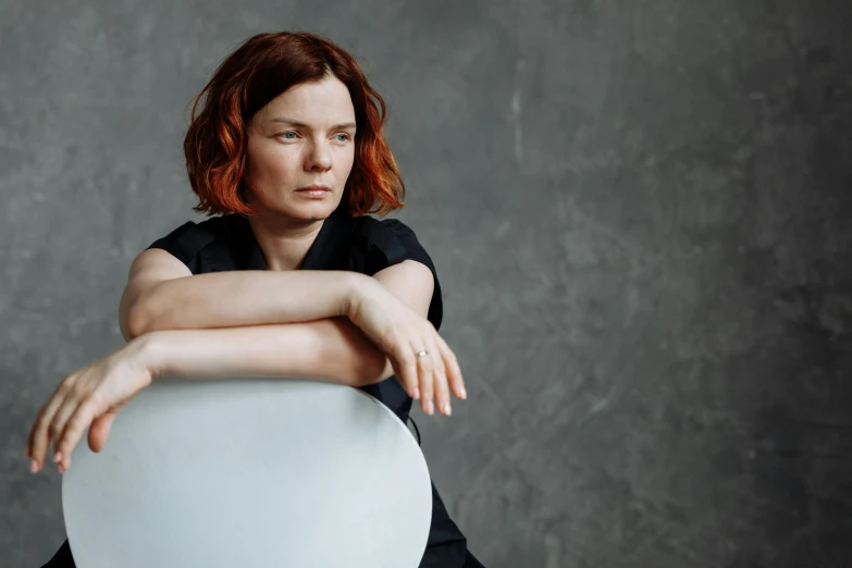 a woman sitting on top of a white chair, a portrait, by Anna Füssli, bauhaus, björk, with red hair, high-quality photo, portrait image