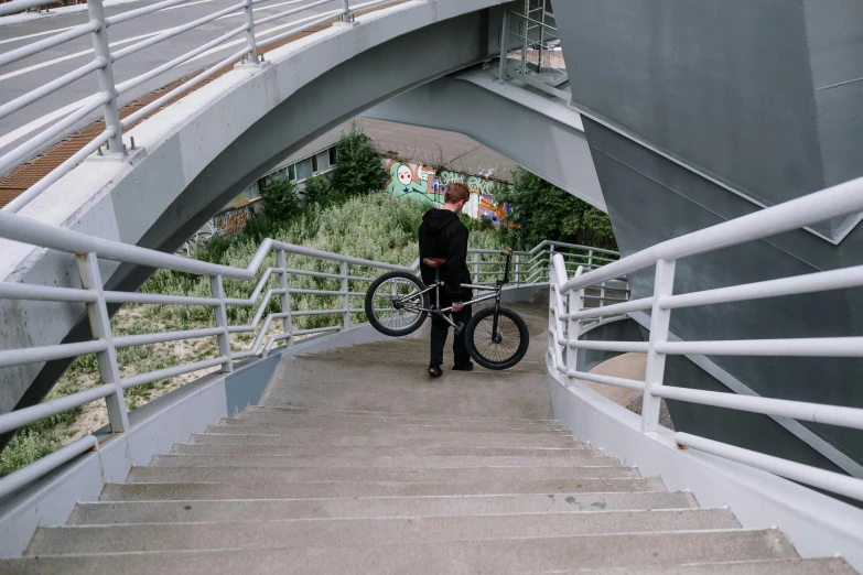 a man carrying a bike up a flight of stairs, unsplash, under bridge, low quality photo, low quality footage, recreation