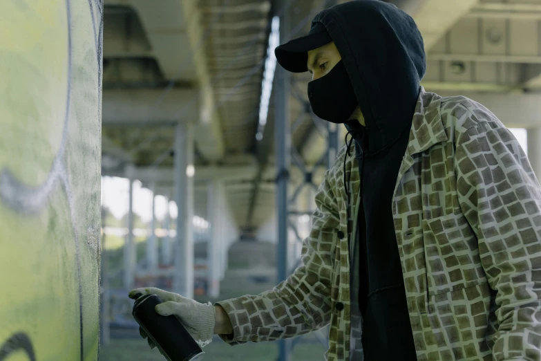 a man in a mask spraying graffiti on a wall, still from a live action movie, vantablack cloak, 🎨🖌️, balaclava