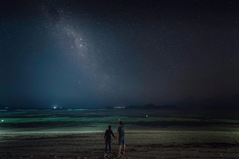 a couple of people standing on top of a sandy beach, unsplash contest winner, realism, on a clear night sky, indonesia, new zeeland, instagram post