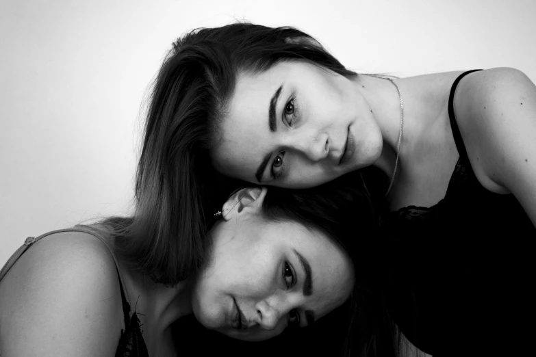 a couple of women standing next to each other, a black and white photo, by Emma Andijewska, unsplash, realism, close - up studio photo, brunettes, laying on their back, two heads