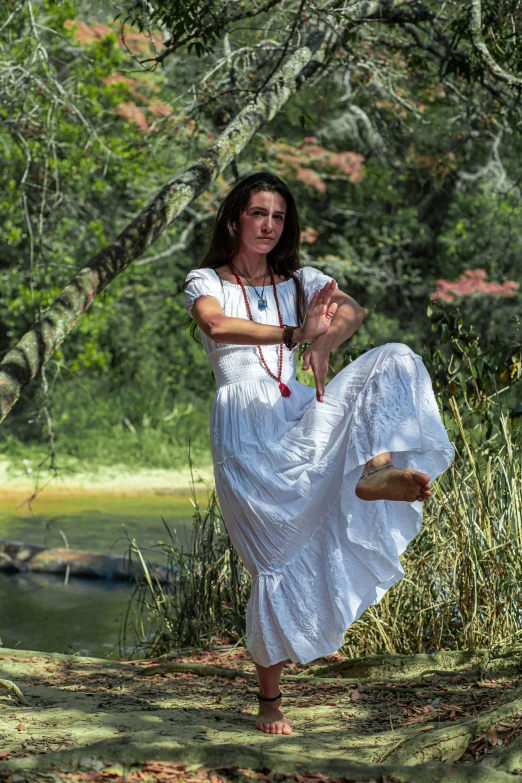 a woman in a white dress standing next to a river, dance meditation, tribal clothing, doing a sassy pose, photograph taken in 2 0 2 0