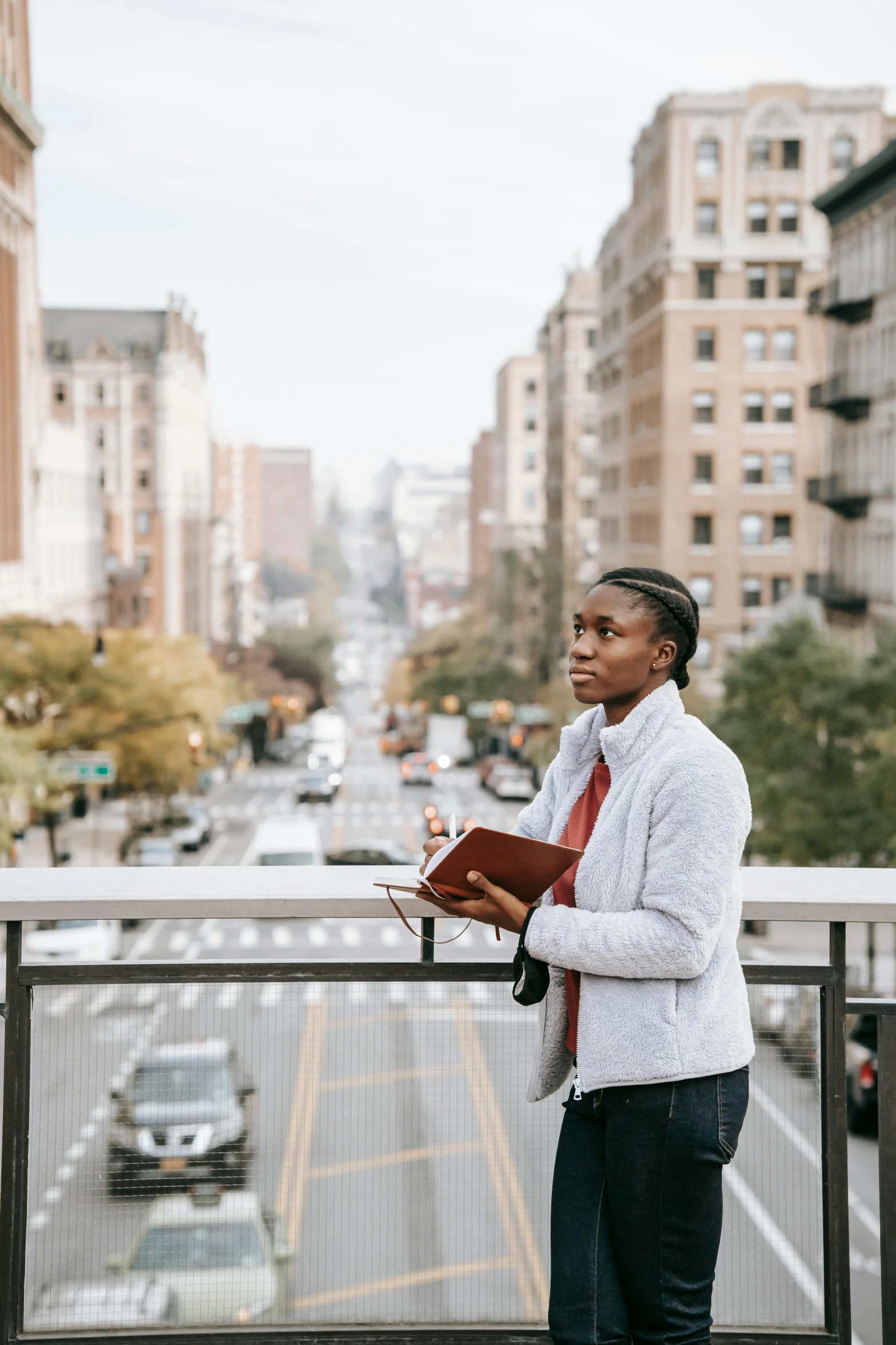 a woman standing on a balcony reading a book, inspired by Ruth Orkin, trending on unsplash, happening, african american young woman, wearing robes and neckties, man walking through city, fall season