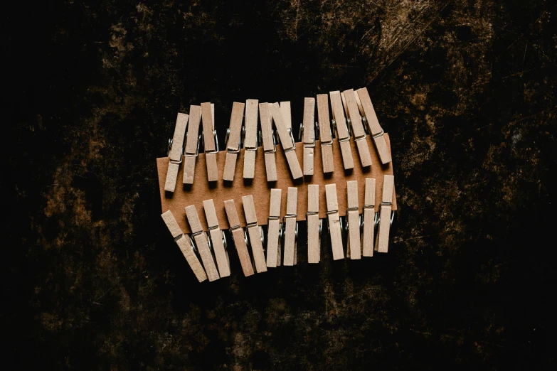 a group of clothes pegs hanging on a clothes line, an album cover, unsplash, conceptual art, wooden match sticks 4k texture, alessio albi, 1 6 x 1 6, brown
