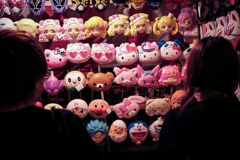 a woman standing in front of a display of stuffed animals, a cartoon, inspired by Hikari Shimoda, tumblr, toyism, tamagotchi, drama masks, 33mm photo, sanrio ornaments