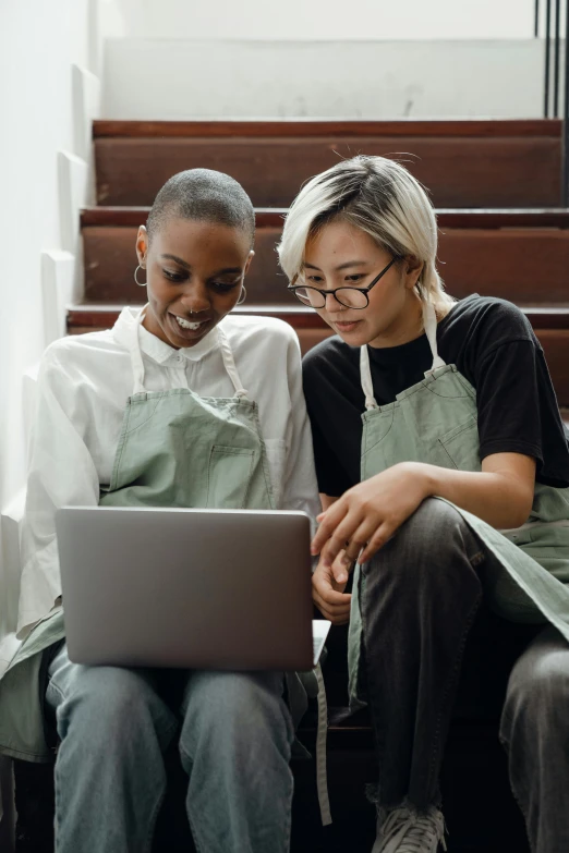 two women sitting on stairs looking at a laptop, trending on pexels, renaissance, wearing an apron, asian descent, inspect in inventory image, ashteroth