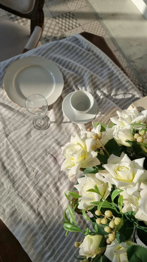 a table that has a bunch of flowers on it, a still life, inspired by Agnes Martin, unsplash, low quality photo, tablecloth, high angle close up shot, morning sun