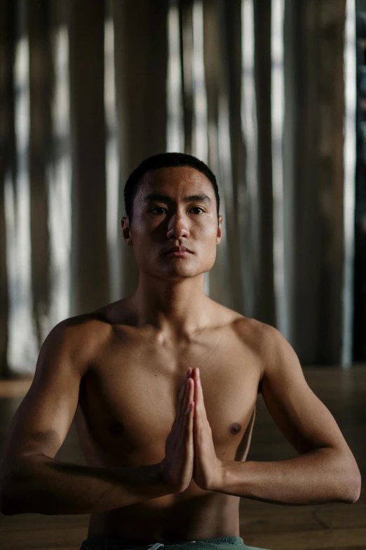 a man sitting in the middle of a yoga pose, a portrait, inspired by Fei Danxu, unsplash, lgbtq, looking towards camera, ignant, sacred
